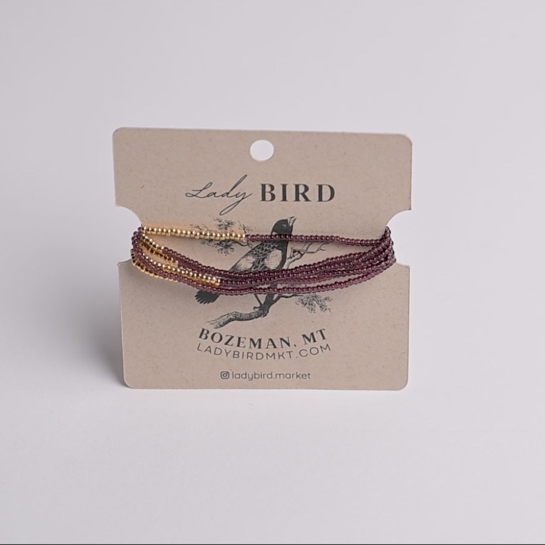 beaded wrap bracelets in gold and dark burgundy on a kraft paper display card from Lady Bird.