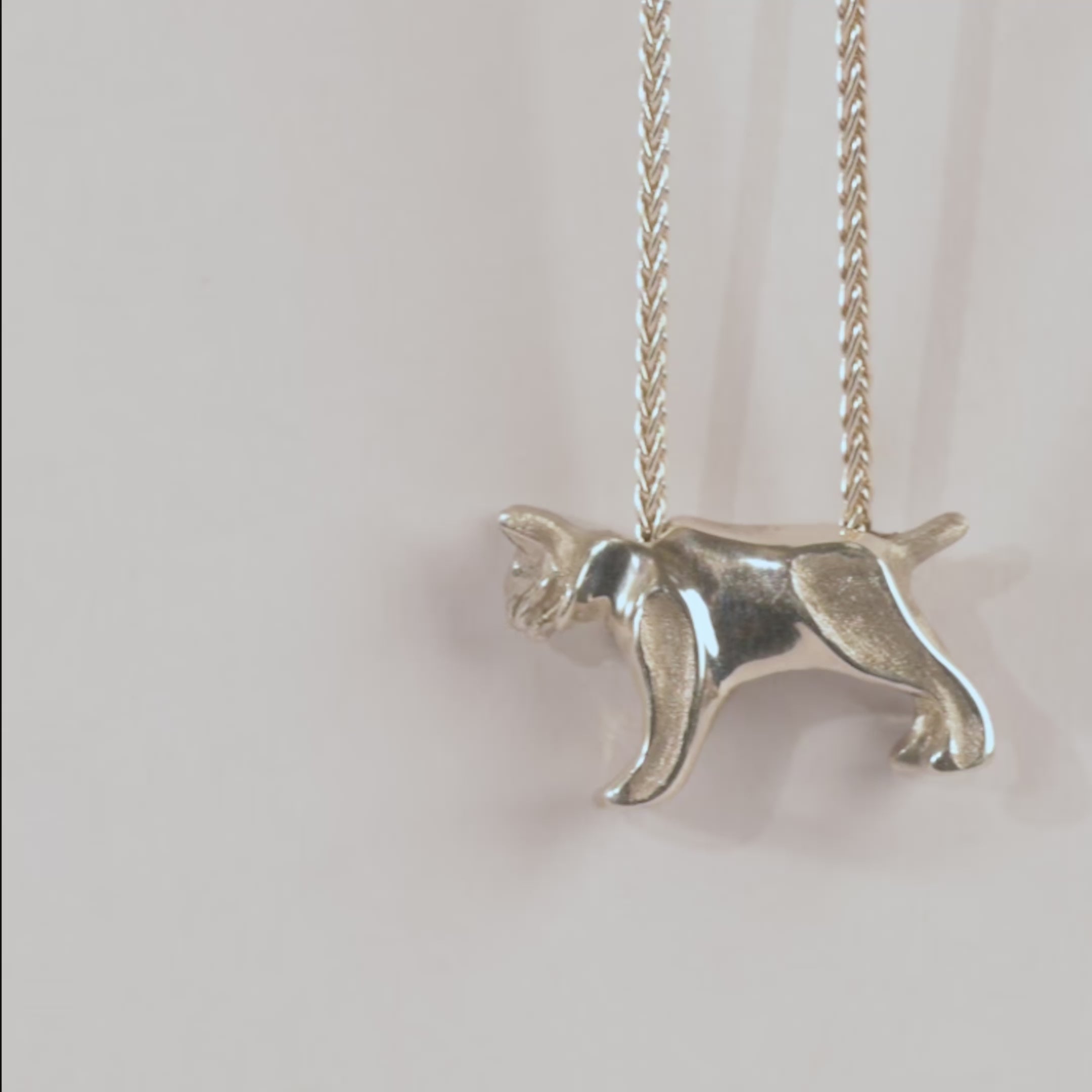 Silver bobcat-shaped pendant on a chain against a white background
