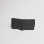 A black textured leather pouch or sleeve with a curved bottom edge and visible stitching, photographed on a clean white background.
