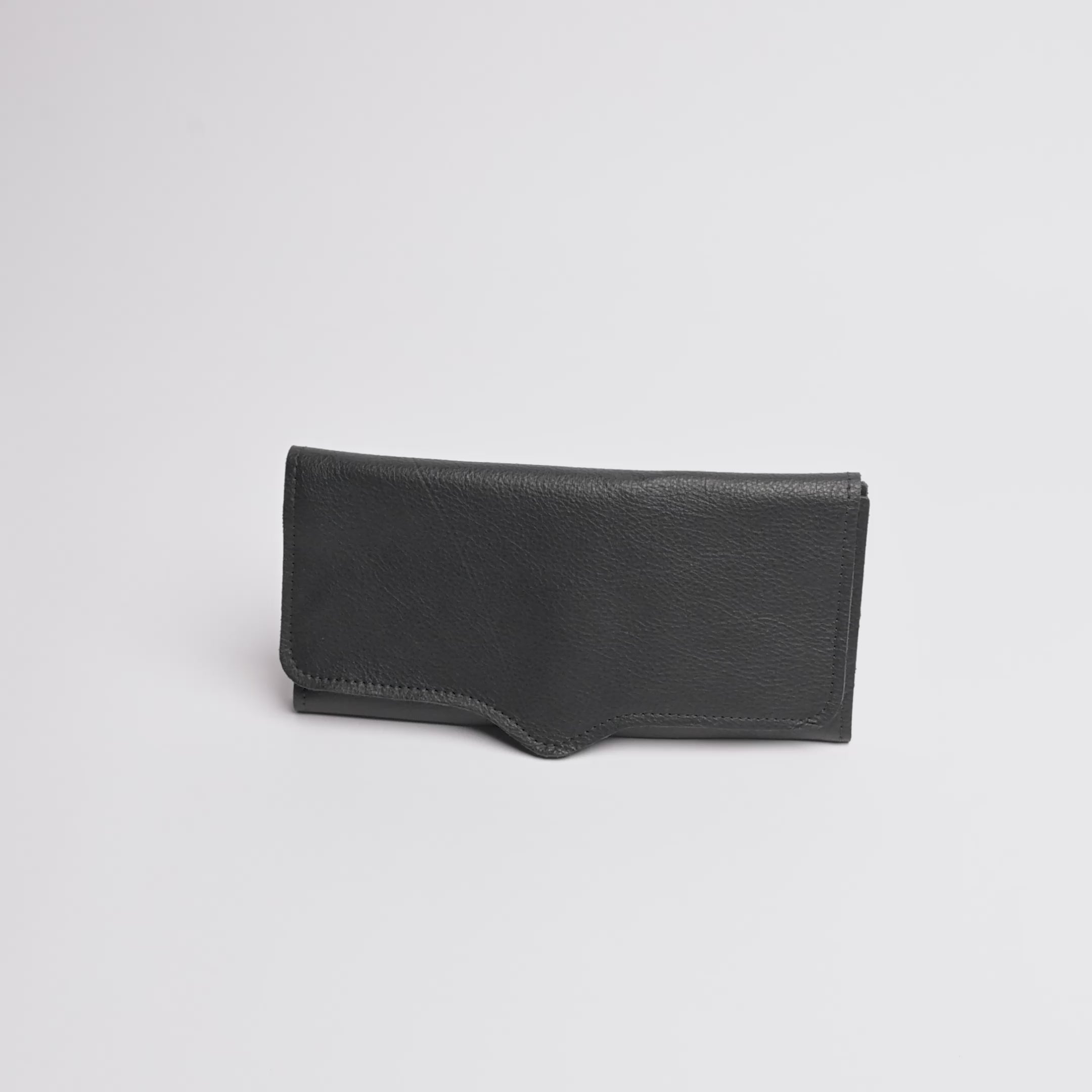 A black textured leather pouch or sleeve with a curved bottom edge and visible stitching, photographed on a clean white background.
