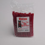 A clear plastic bag of Montana Classic Red Fossil Licorice, showing the red licorice sticks inside. The front features a white label with a black bear logo and red text.