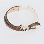Bracelet with silver elk charm and brown leather strap on a white background