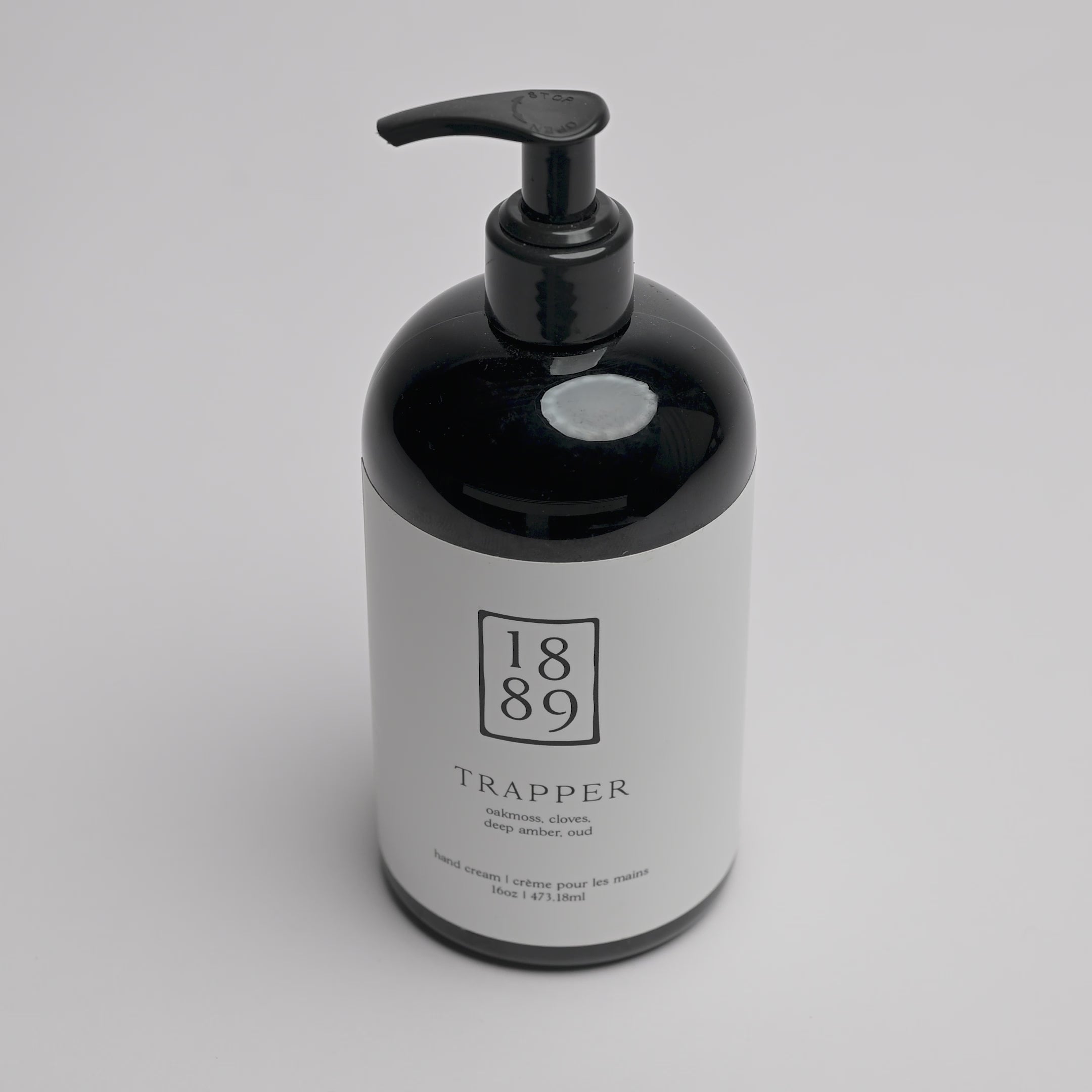 A 1889 brand Trapper hand cream bottle with a glossy black body and pump dispenser, featuring a white label with black text, set against a clean white background.