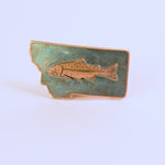 Metallic fish emblem on a blue Montana-shaped belt buckle on a white background