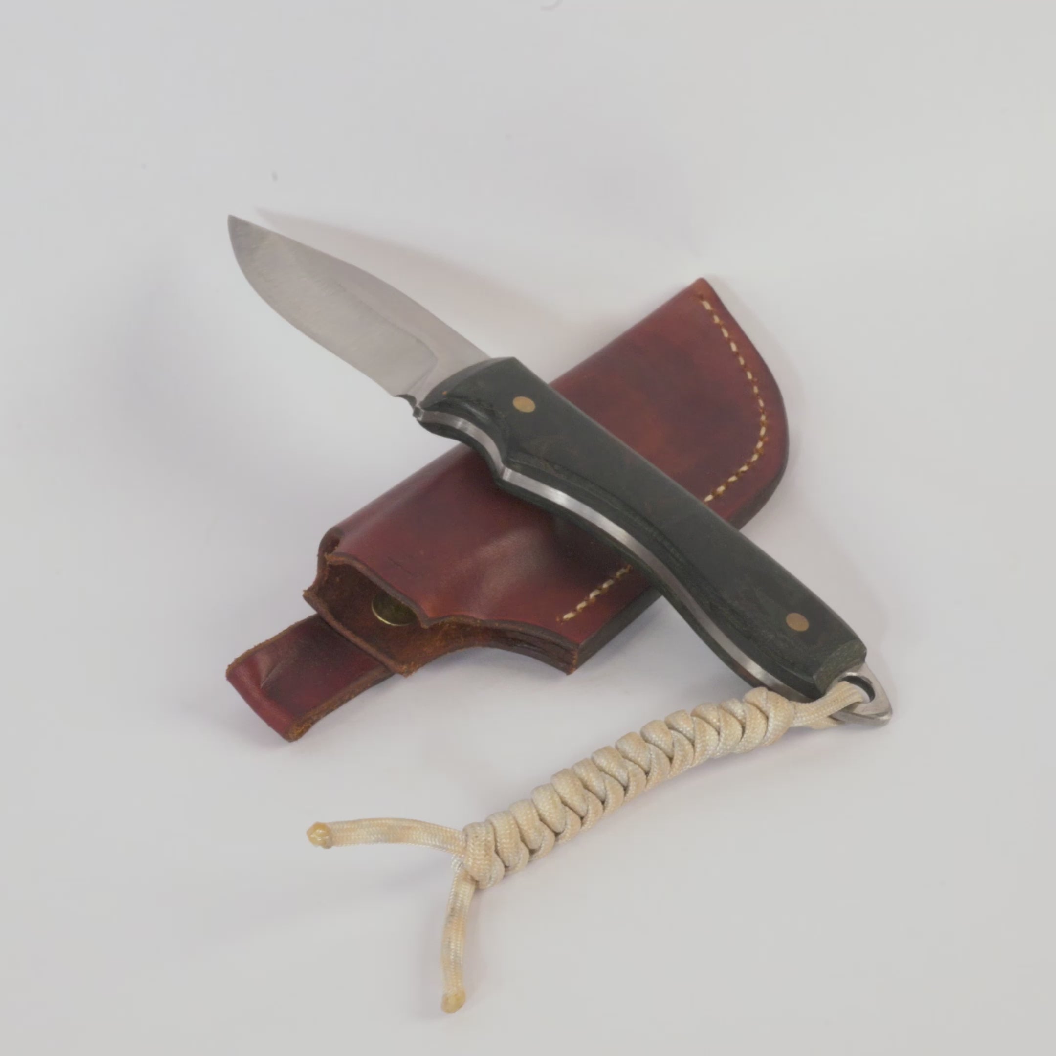 Knife with leather sheath and rope lanyard on a white background