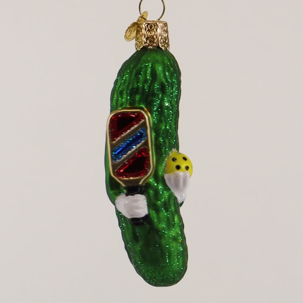 Decorative pickle ornament with a pickleball paddle on a white background