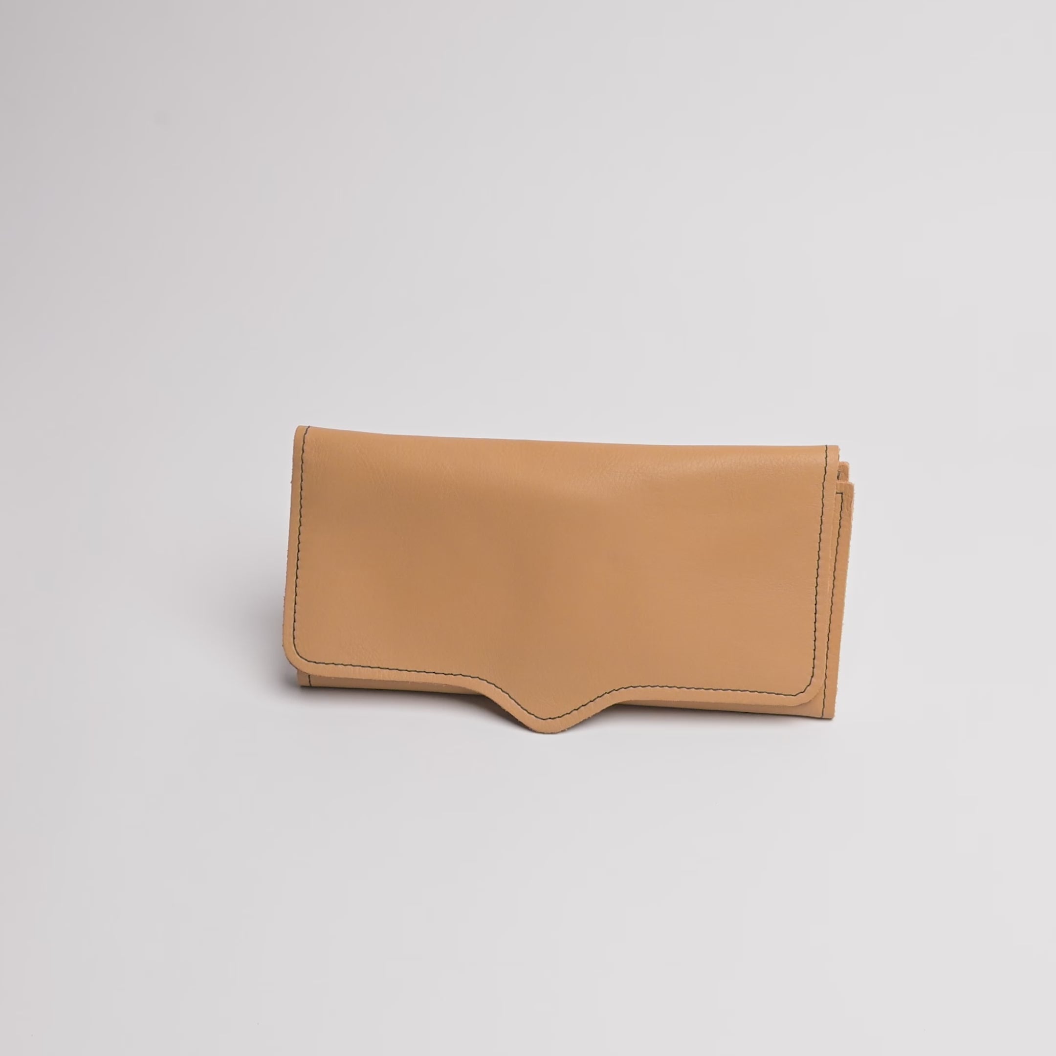 A tan leather pouch or wallet with visible stitching, photographed on a clean light gray background.