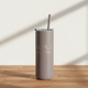 Gray tumbler with straw on a wooden surface and light background
