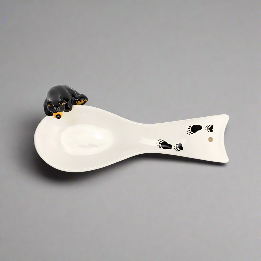 The Bearfoots Bear Spoon Rest by Jeff Fleming features a white ceramic spoon rest with one of Fleming's famous Bearfoots bears perched upon it! 