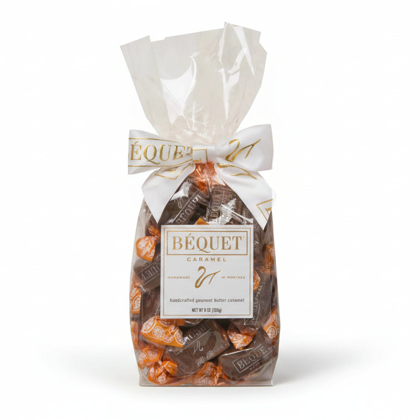 A 4 oz gift bag of Chocolate A L'Orange Caramels by Bequet Confection, with a clear view of the caramels inside the bag which is tied with a white ribbon.