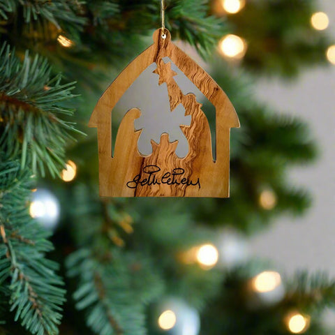 The Medium Nativity House Ornament by Earthwood features a barn shape design with a hand-carved nativity scene inside, all part of an olive wood ornament.