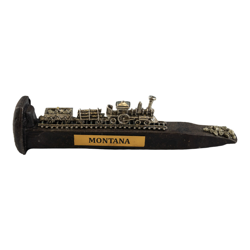 The Montana Railroad Spike with Train by Western Woods Distributing features a carved train on a railroad spike, depicting the scene on May 9, 1880,  when the first tracks were laid over the Continental Divide at the border between Idaho and Montana.
