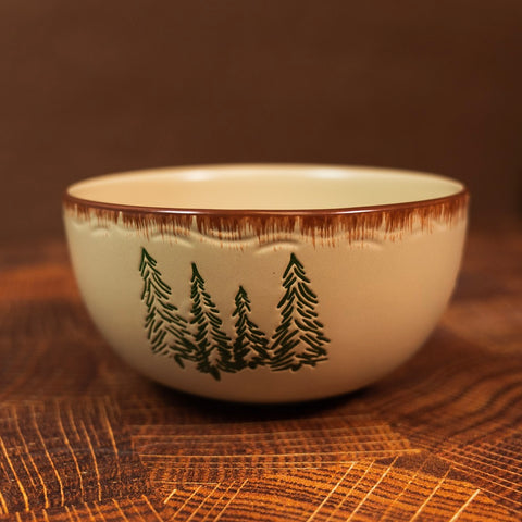 The Rustic Retreat Cereal Bowl by Park Designs features a stoneware ceramic bowl with sgraffito (an Italian term for carving out an image) trees on the sides.