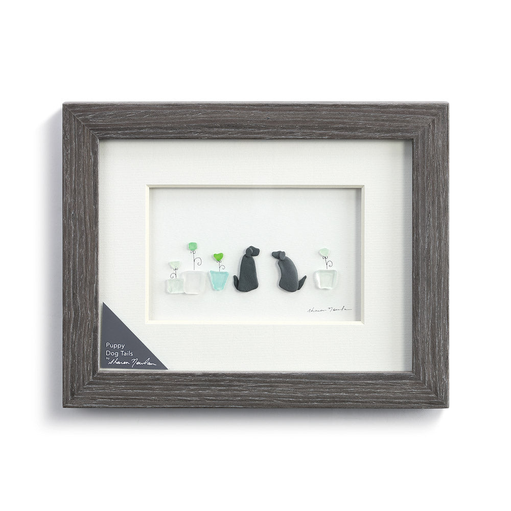 The Sharon Nowlan Puppy Dogs Tails Wall Art by Demdaco gives you the beautiful image of two dogs sitting next to some potted plants!